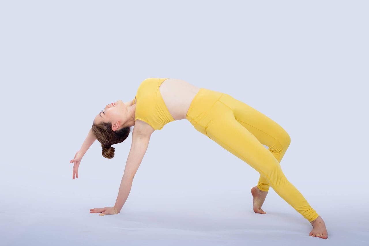 The Art of Drawing Readers In: Your attractive post title goes here Athletic woman in yellow sportswear posing gracefully in an acrobatic move on a white background.