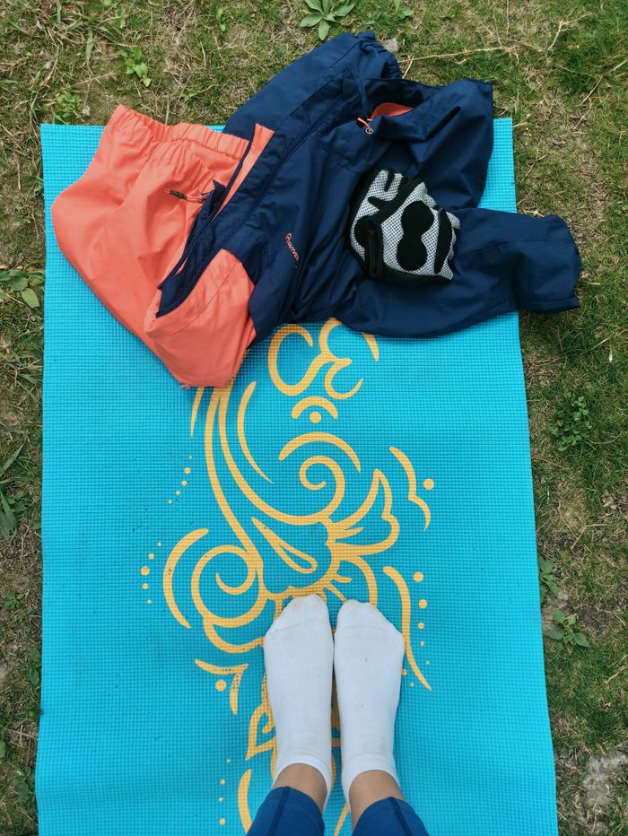 Offerings Person standing on blue yoga mat outdoors with clothes laid out.